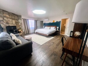 A bedroom with a bed, a sofa, a dining table, and a stone wall. - NEW! MiniGolf–PoolTable–FirePit–BBQ–Arcade–Bocce (Page)
