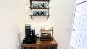 A coffee station with a Keurig machine, a coffee bar sign, and a shelf with mugs. - NEW! MiniGolf–PoolTable–FirePit–BBQ–Arcade–Bocce (Page)