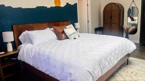A bedroom with a large bed, a nightstand, a lamp, a mirror, and a wardrobe. - NEW! MiniGolf–PoolTable–FirePit–BBQ–Arcade–Bocce (Page)