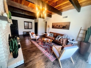 A cozy living room with a brown leather sofa, a patterned rug, and a wooden ceiling. - NEW! MiniGolf–PoolTable–FirePit–BBQ–Arcade–Bocce (Page)