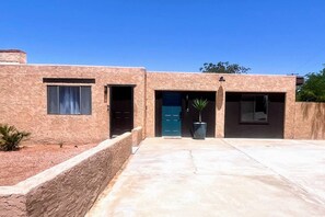 A two-story building with a stucco exterior, a blue door, and a potted plant in the entrance. - NEW! MiniGolf–PoolTable–FirePit–BBQ–Arcade–Bocce (Page)