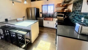 A modern kitchen with a central island, stainless steel appliances, and a window providing natural light. - NEW! MiniGolf–PoolTable–FirePit–BBQ–Arcade–Bocce (Page)