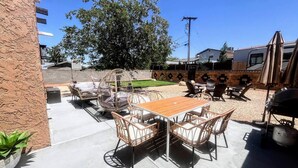 An outdoor patio with a wooden table and wicker chairs, a grill, and a hanging chair. - NEW! MiniGolf–PoolTable–FirePit–BBQ–Arcade–Bocce (Page)