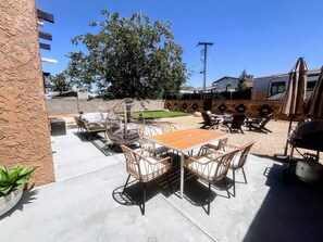 An outdoor patio with a wooden table and wicker chairs, a grill, and a hanging chair. - NEW! MiniGolf–PoolTable–FirePit–BBQ–Arcade–Bocce (Page)