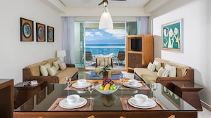 A modern hotel room with a dining area, two sofas, a TV, and artwork on the walls. - Charming 2-bedroom Suite with fitness room and AC in gorgeous Nuevo Vallarta (Nuevo Vallarta)