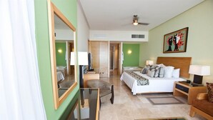 A hotel room with a bed, a desk, a chair, a mirror, a ceiling fan, and artwork on the wall. - Charming 1-bedroom Studio with fitness room and AC in Nuevo Vallarta (Nuevo Vallarta)