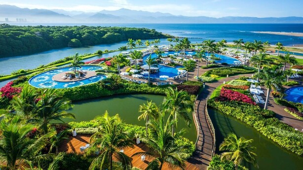 A resort with multiple swimming pools, palm trees, and a view of the ocean and mountains. - Charming 1-bedroom Studio with fitness room and AC in Nuevo Vallarta (Nuevo Vallarta)