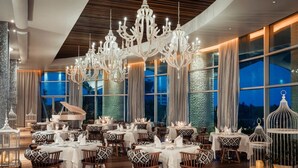 A restaurant with multiple tables set for dining, large windows, and a grand chandelier. - Charming 1-bedroom Studio with fitness room and AC in Nuevo Vallarta (Nuevo Vallarta)