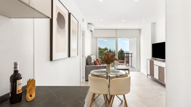 Een moderne woonkamer met een eethoek, een televisie en kunstwerken in lijsten aan de muur.