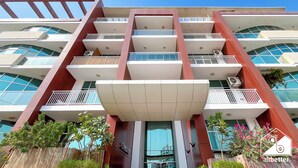 Un edificio de varios pisos con balcones, ventanas amplias y un cielo despejado.