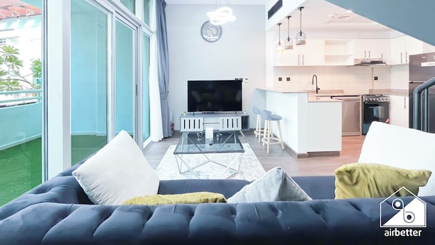 Una sala de estar moderna con un sofá grande, un televisor y una mesa de centro de vidrio.
