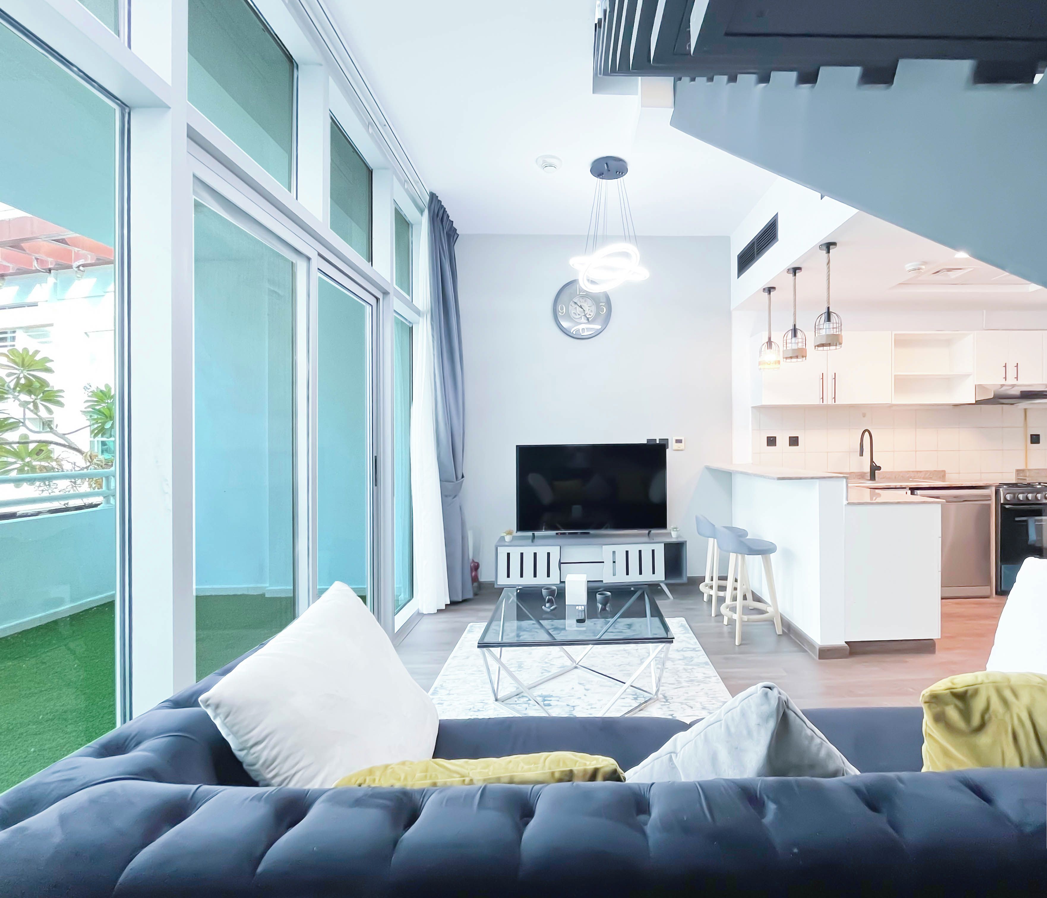 A modern living room with a large sofa, a TV, and a glass coffee table.
