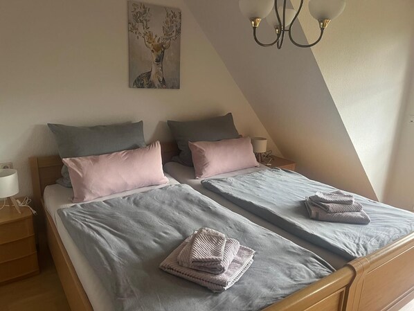 A twin bedroom with two beds, each with a pillow and a folded towel. - Vacation apartment with pony farm 🐴🐶🐓 (Edertal)