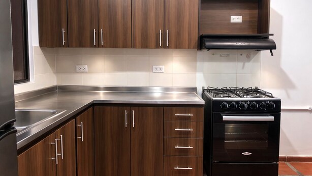 A kitchen with dark wood cabinets, a stainless steel countertop, a black gas stove, and a built-in oven. - Room AREAS by QuBeLab (Bello)
