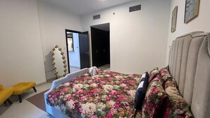 Un dormitori amb un llit, una cadira i una porta que dona a una altra estança.