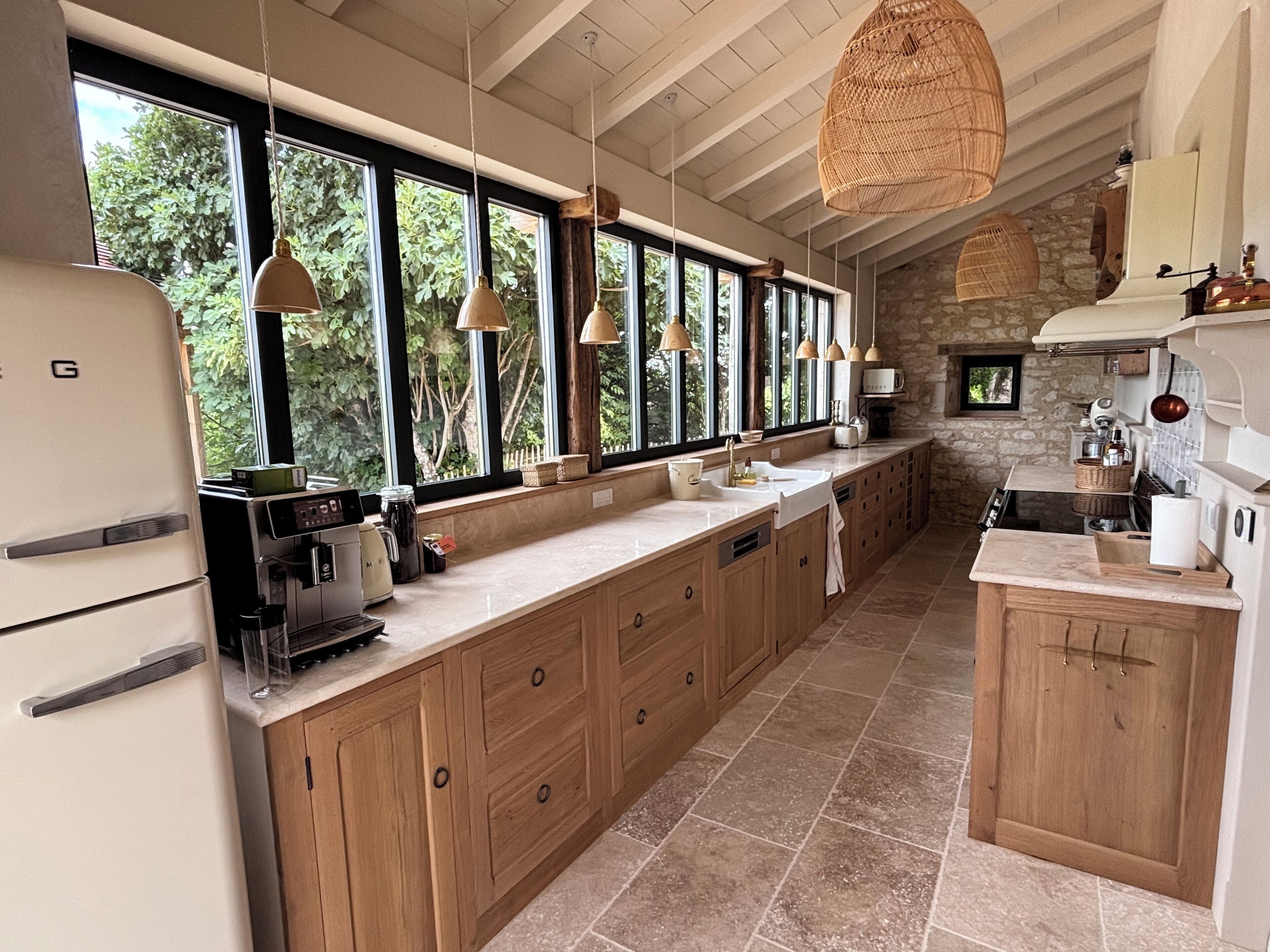 A spacious kitchen with wooden cabinets, a large island, and a stone wall.