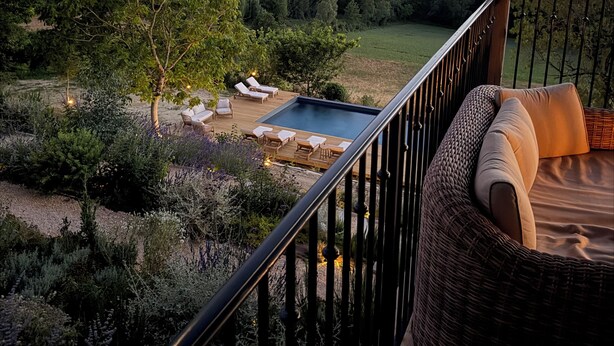 A balcony with a wicker sofa, a small pool, and a view of a forested landscape. - 15th-Century farmhouse in the hills of Occitanie (Lauzerte)