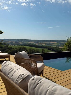 A wooden deck with wicker furniture and a swimming pool. - 15th-Century farmhouse in the hills of Occitanie (Lauzerte)
