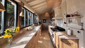 Une cuisine moderne dotée de grandes fenêtres, de meubles en bois et d’un pare-feu en pierre.