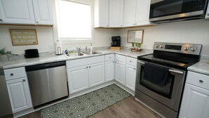 A modern kitchen with white cabinets, stainless steel appliances, a dishwasher, a microwave, and an oven. - Comfortable 4BR Home Near Downtown Elyria (Elyria)