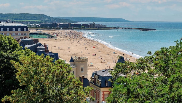 A coastal town with a beach, buildings, and a pier.