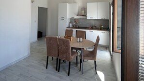A modern kitchen with white cabinets, a dining area with a round table and chairs, and a wooden floor.