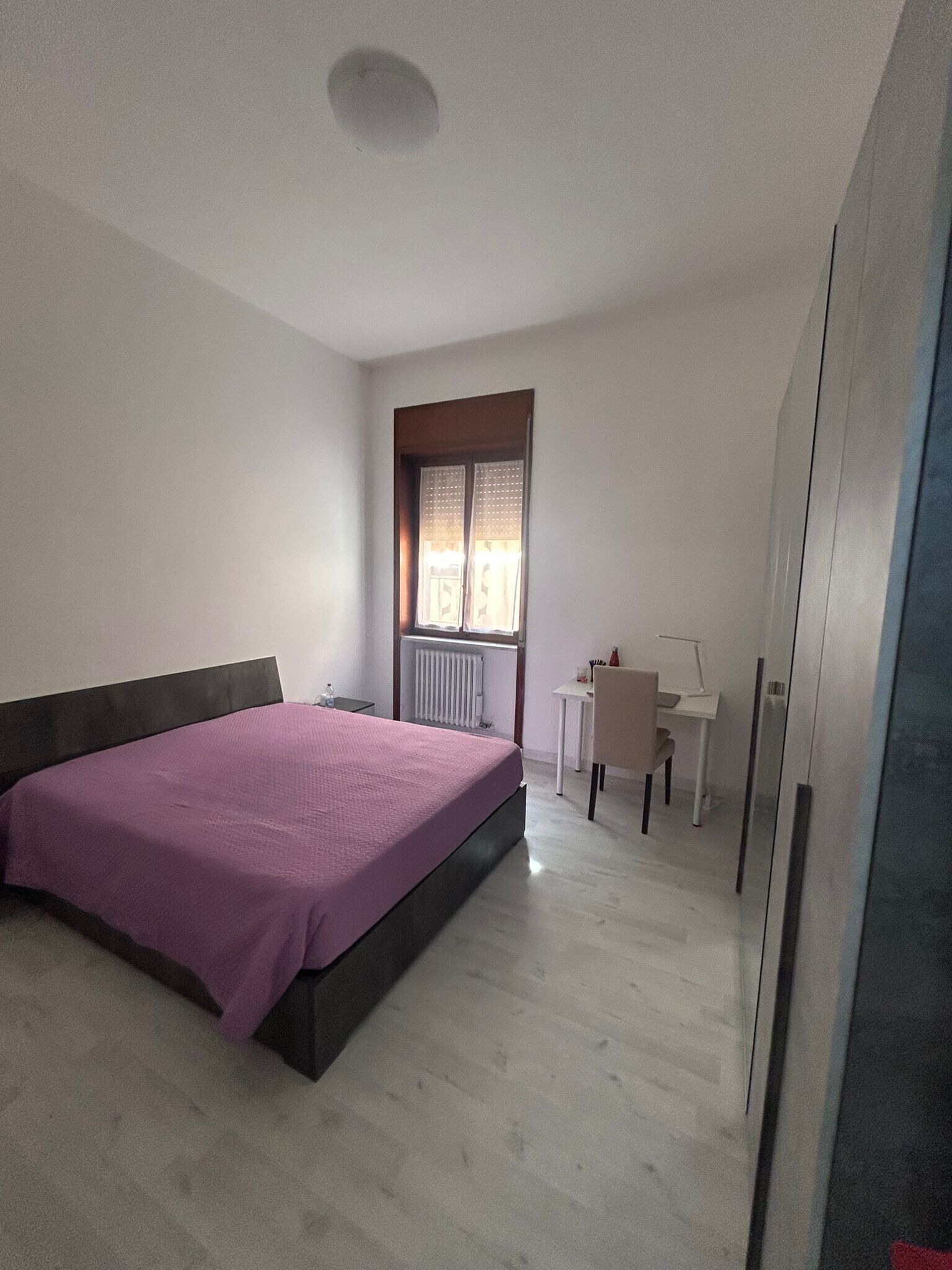 A bedroom with a bed, a desk, and a chair.