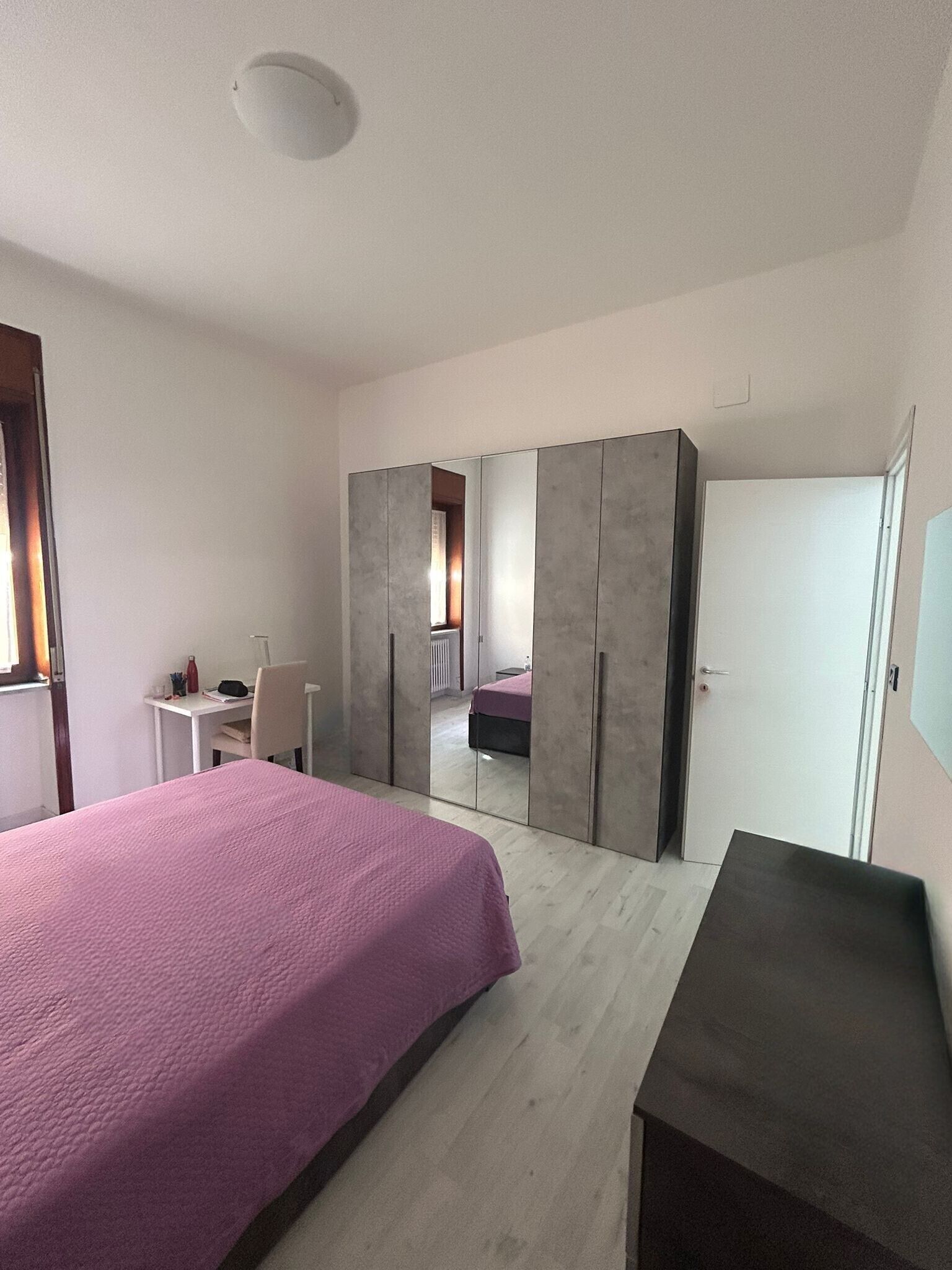 Ein Schlafzimmer mit Bett, Schreibtisch, Kleiderschrank und Spiegel.