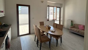 A modern living space with a dining area, kitchen, and a sofa.