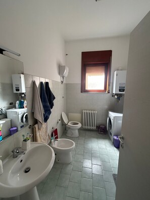 A bathroom with a toilet, bidet, sink, and washing machine. - Apartment 'Rob' with Private Terrace and Air Conditioning (Lecce)