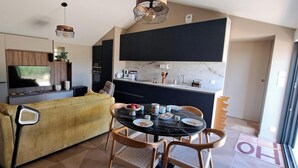 Een moderne woonruimte met een bank, eettafel, stoelen en een keuken met kasten en apparatuur.
