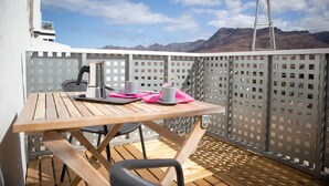 A wooden deck with a table, chairs, and a coffee maker.