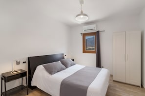 Ein Schlafzimmer mit Bett, Nachttisch, Kleiderschrank und Klimaanlage.