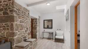 A room with a stone wall, a white chair, a small table, and a mirror on the wall.