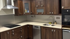 Una cocina moderna con armarios de madera oscura, electrodomésticos de acero inoxidable y una encimera de color claro.