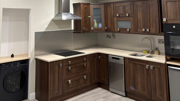 Una cocina moderna con armarios de madera, lavavajillas integrado y tragaluz.