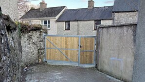 Un patio empedrado con una puerta de madera, muros de piedra y suelo de ladrillo.