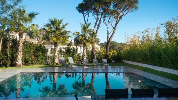 A swimming pool with lounge chairs and a stone wall in the background. - Villa Saint Aygulf - Vue mer avec Piscine Privée (Saint-Aygulf)