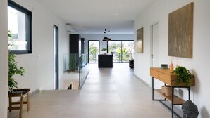 A spacious hallway with a modern design, featuring a wooden bench, a console table with a plant, and a large abstract painting on the wall. - Villa Saint Aygulf - Vue mer avec Piscine Privée (Saint-Aygulf)