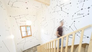 A staircase with a wooden handrail and a wall with star constellations.