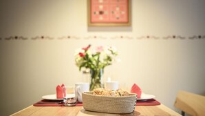 A dining table with a basket of cookies, a glass of water, and a vase of flowers.