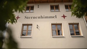 A building with the name "Sternenheimel" on the facade, featuring three windows and a wooden roof.