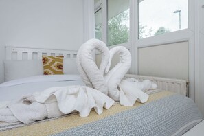 A bed with a white headboard, a patterned pillow, and a blanket with a geometric pattern.