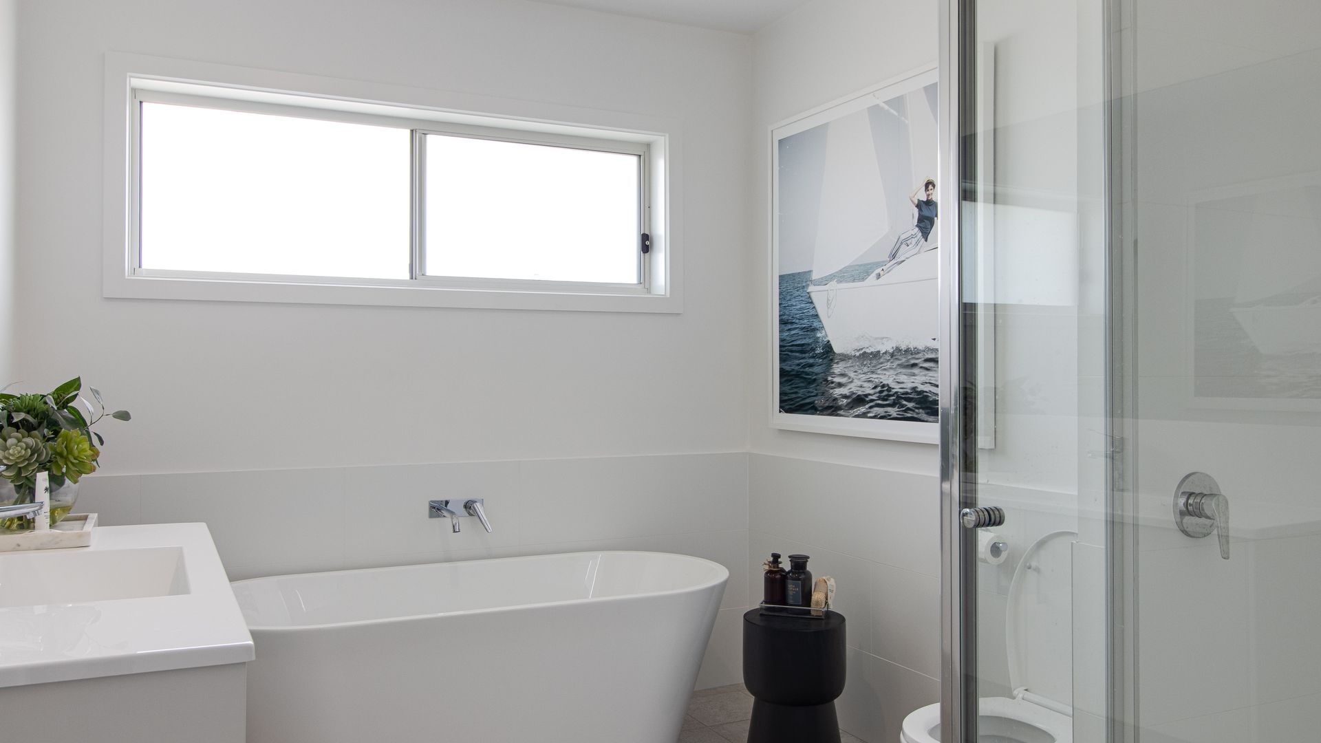 Een moderne badkamer met een vrijstaand bad, toilet en een douchecabine met glazen wanden.