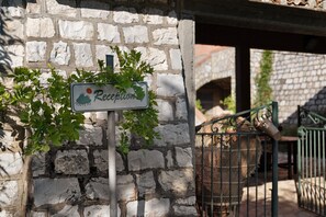 Un panneau d’accueil orné d’un pictogramme de montagne, un mur en pierre et un portail en métal.