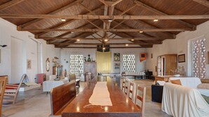 A spacious hall with a long wooden table, benches, and a high wooden ceiling.