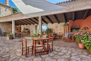 Une terrasse extérieure rustique avec un sol en pierre, des meubles en bois et des plantes en pot.