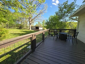 A wooden deck with a table and chairs, surrounded by a metal fence and trees. - Charming Mountain Retreat with fire pit, fenced yard, scenic views, and privacy. (Mineral Bluff)