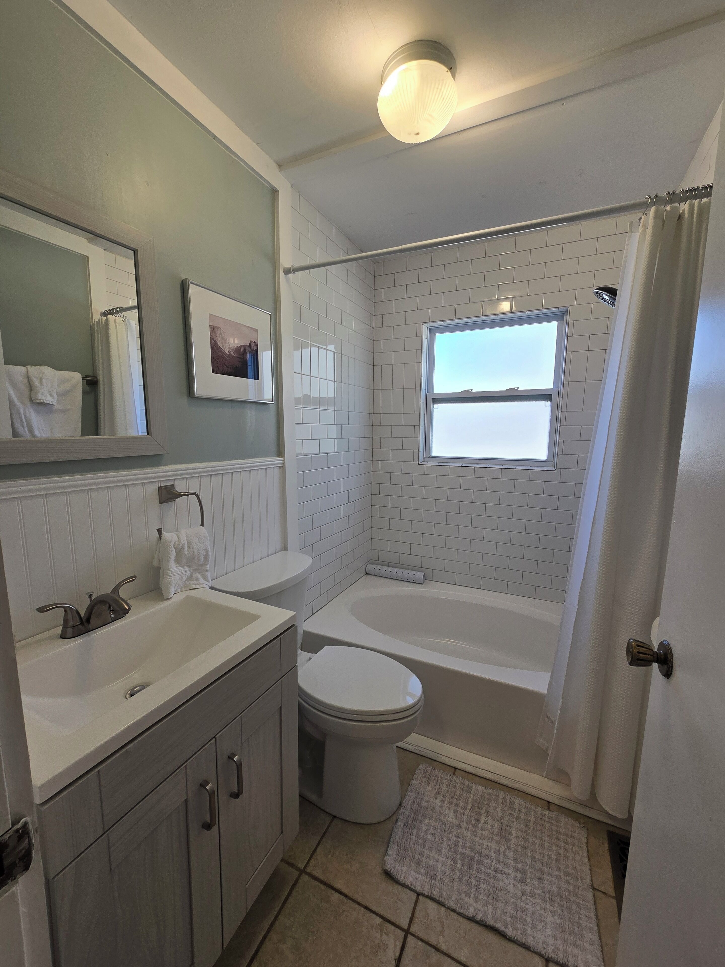 Une salle de bain avec un lavabo, des toilettes, une baignoire et une fenêtre.