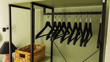 A metal rack with multiple hangers and a woven basket on a shelf.